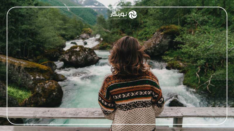 ایستادن روی پل چوبی و نگاه به رودخانه