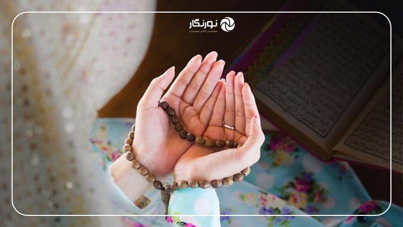 کلوزآپ از دانه‌های تسبیح در دست فردی که در حال دعا است